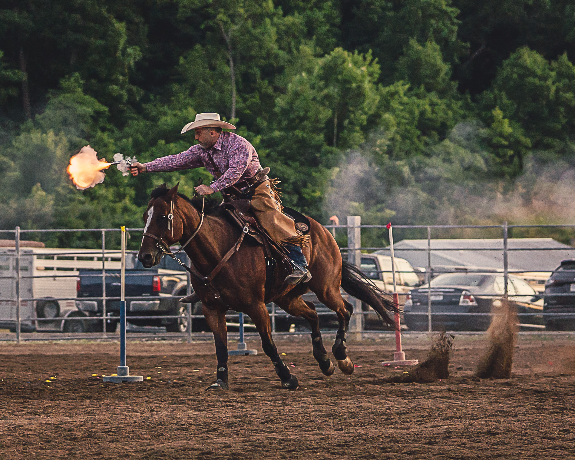 Man in cowboy hat shooting a pistol on horseback